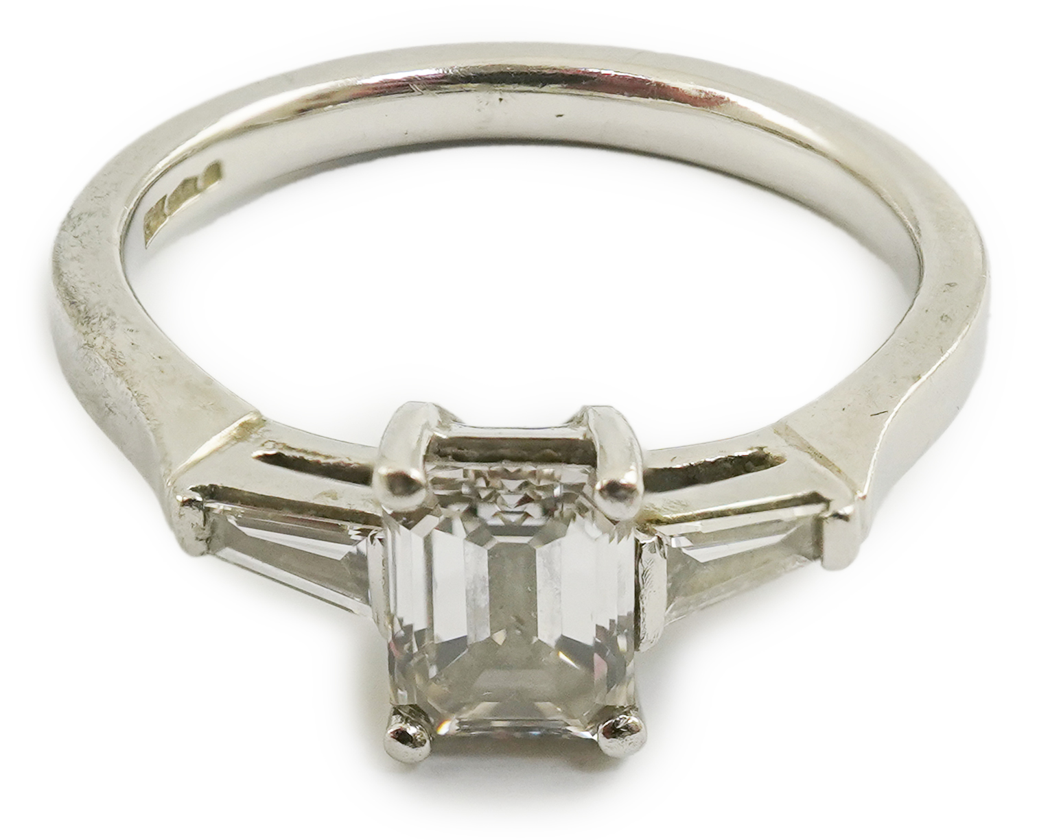 A modern platinum and single stone emerald cut diamond set ring, with two stone tapered baguette cut diamond set shoulders